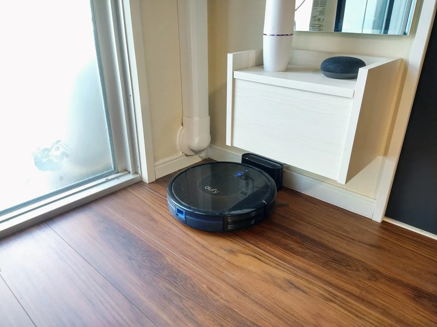 木の床の上を走るロボット掃除機と、その充電ドック