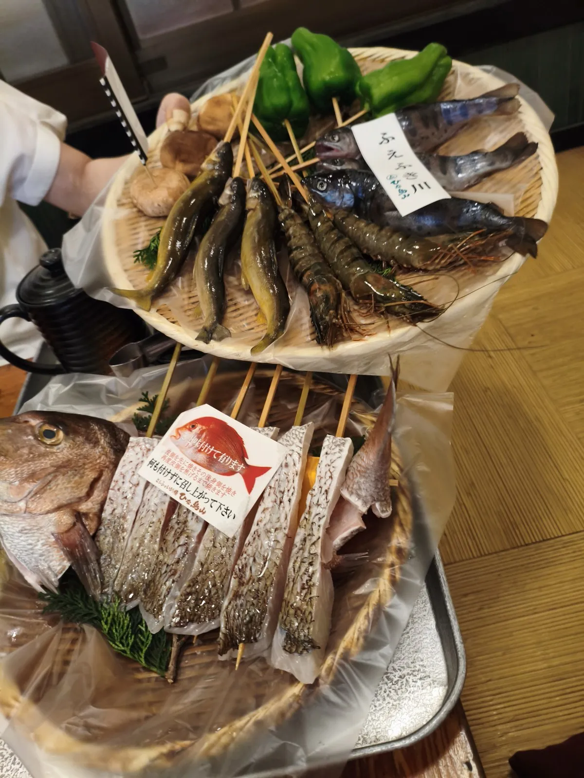 桶と器に並んだ鮎、海老、椎茸、ピーマンなどの食材